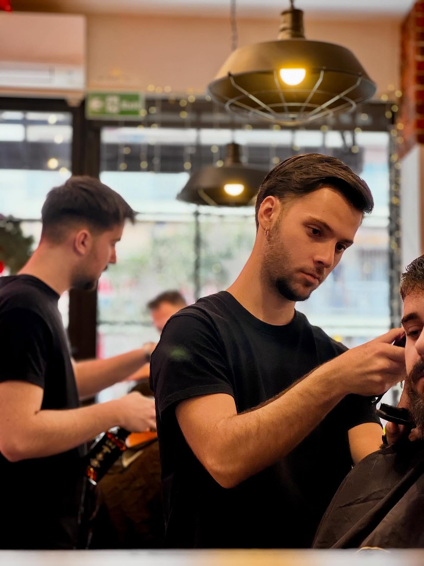Δύο barbers του Galinos κουρεύουν ταυτόχρονα κάτω από τα ζεστά φωτιστικά