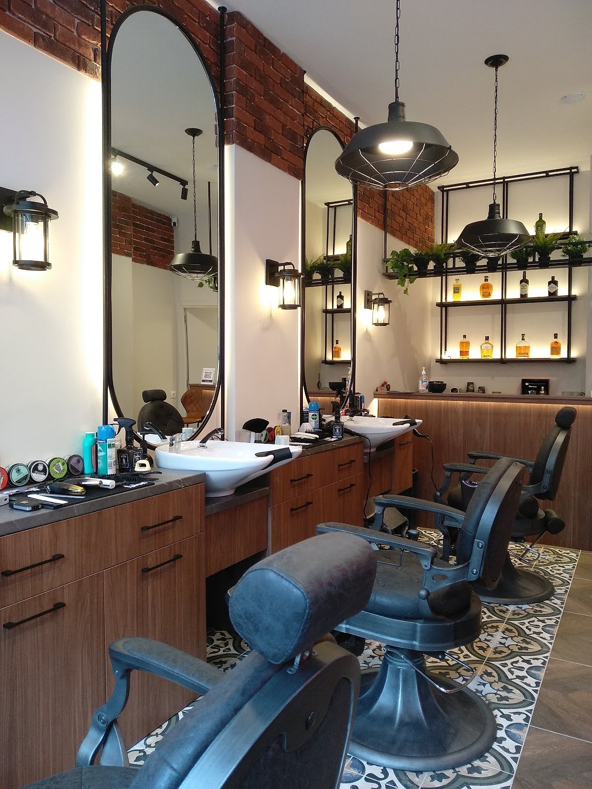 Ο χώρος του Galinos Barbershop με τους ψηλούς μαύρους καθρέφτες, τους ξύλινους πάγκους και τα πλακάκια με μοτίβο